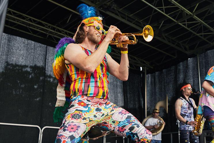 A person dressed in colourful feather performing on stage with a trumpet