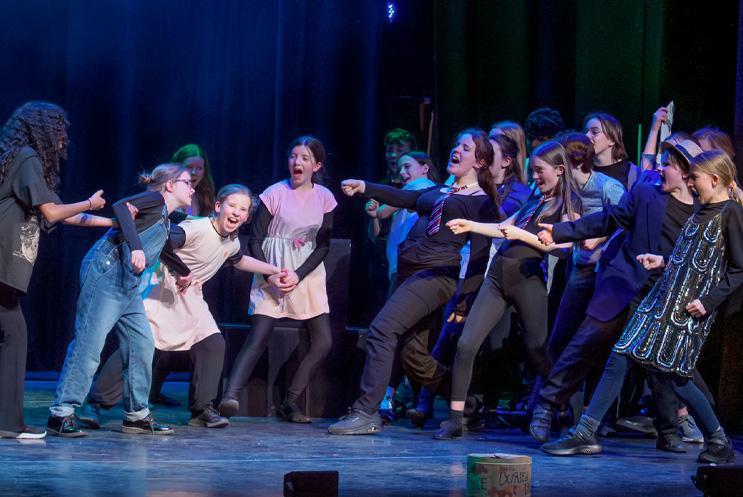 Group of young performers doing physical theatre on stage