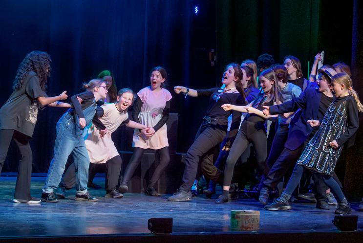 Group of young performers doing physical theatre on stage