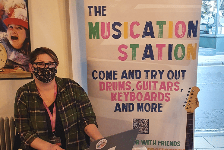 Person behind a pull up banner which displays Muscation Station