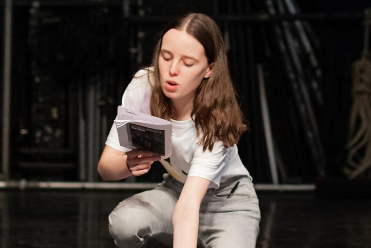 girl reading from a script on stage