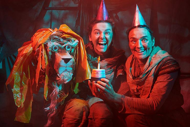 Performers wearing birthday hats with puppet Lion