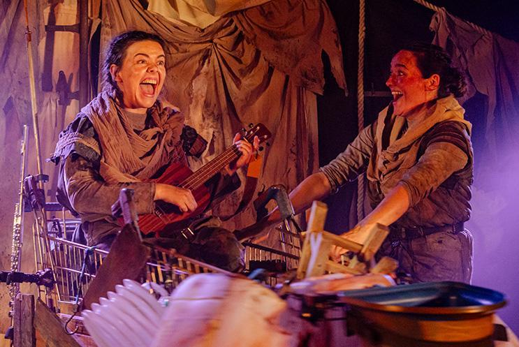 Performers laughing and happy, one is sat in a trolley