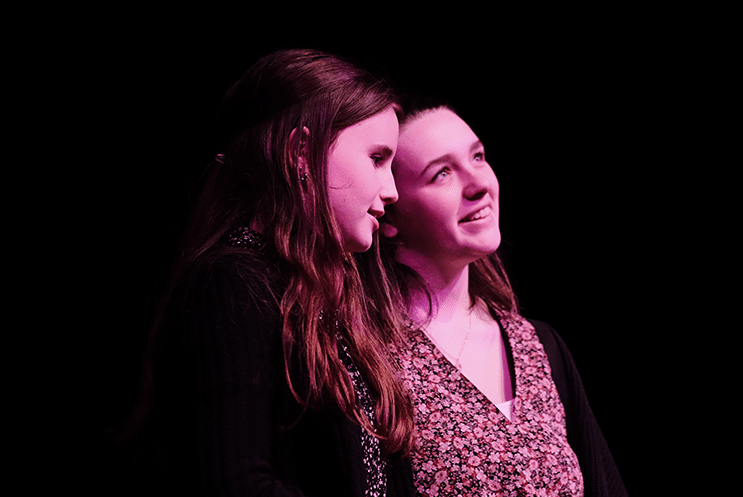 Two young people lit under a pink light