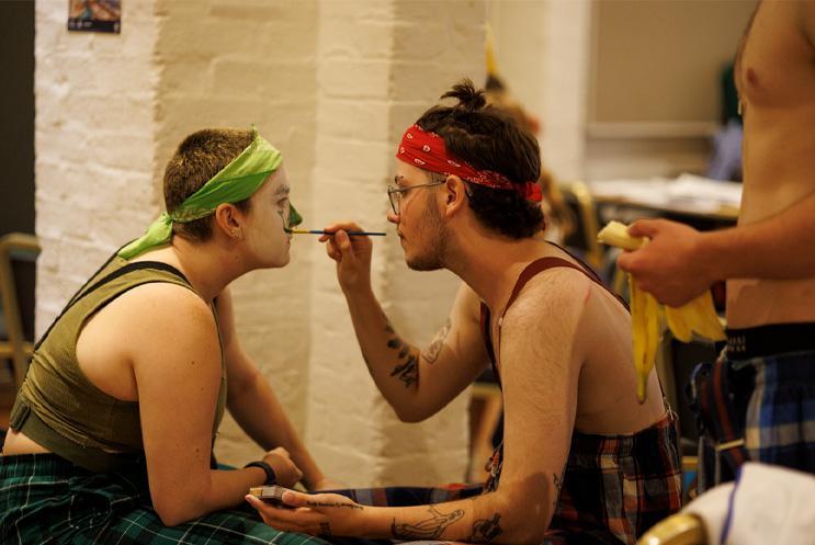 Young artists applying clown make-up backstage