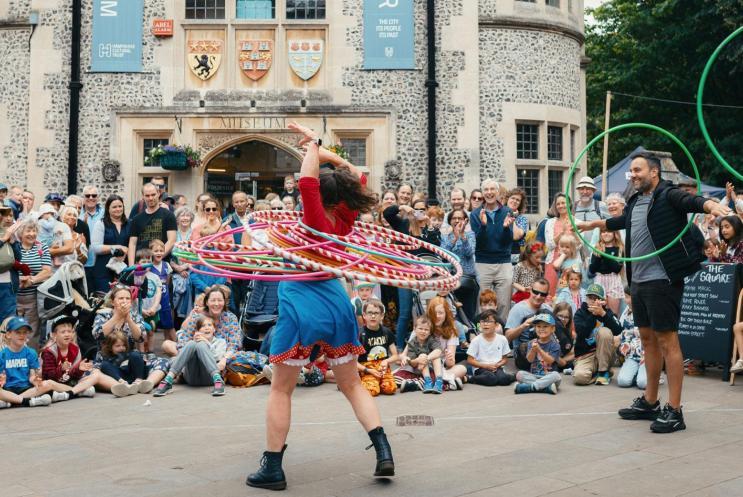 A hula hoop artist, performing to a large crowd outside