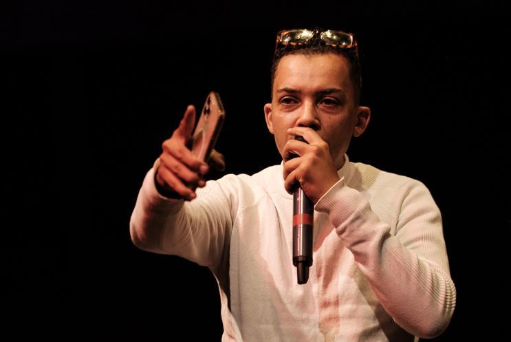 Man in white long sleeve T-shity with mic in his hand pointing at audience