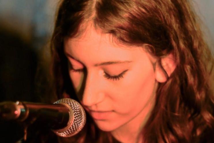 Person with long hair looking down at a microphone