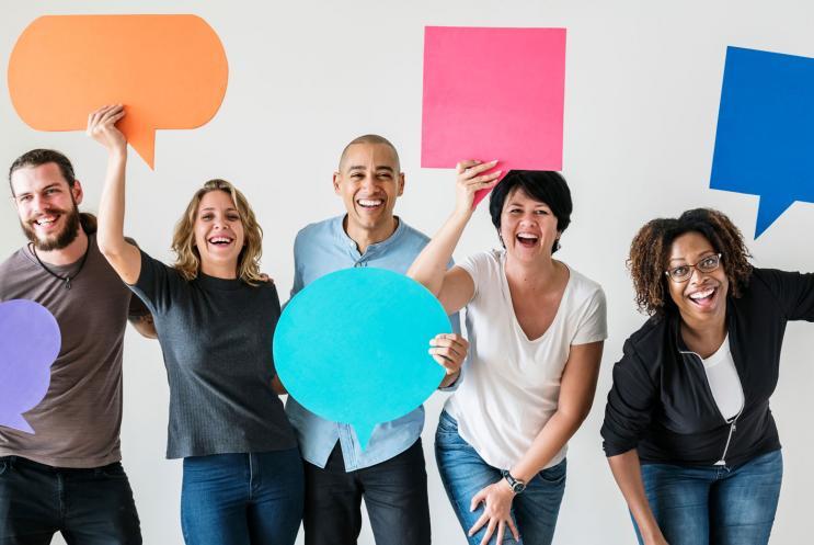 A small group of men and woman holding up colourful speech bubbles